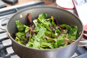 swiss chard and sauteed onions in a pan