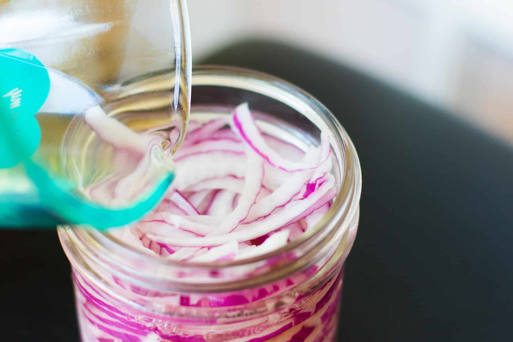 pouring hot water and vinegar over onions